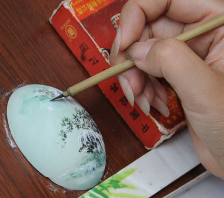 Tao Rong, a crafts artist from Sichuan Province, draws on an egg shell in the ancient Jinli street in Chengdu, capital of southwest China&apos;s Sichuan Province, Aug. 24, 2009.(Xinhua Photo)
