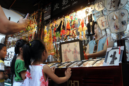 Folk artist Zhou Wei plays shadow puppet in the ancient Jinli street in Chengdu, capital of southwest China's Sichuan Province, Aug. 24, 2009.(Xinhua Photo)