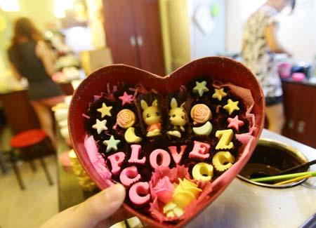 A woman customer shows her own style chocolates for the coming Chinese Valentine's Day at a handicraft chocolate shop in downtown Hangzhou, east China's Zhejiang province, August 18, 2009. These fashionable women will welcome the Chinese Valentine's Day on August 26, 2009 with their individual style chocolates for their lovers.(Xinhua Photo)