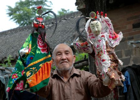 Yuan Youen, a folk artist, shows puppets of Shoulder Pole Drama, a local traveling puppet drama show the performer of which loads the stage property by a shoulder pole, in Balizhuang Village in Neihuang County, central China&apos;s Henan Province, Aug. 23, 2009. 