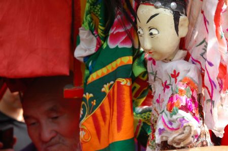 Yuan Youen, a folk artist, performs Shoulder Pole Drama, a local traveling puppet drama show the performer of which loads the stage property by a shoulder pole, in Balizhuang Village in Neihuang County, central China's Henan Province, Aug. 23, 2009.