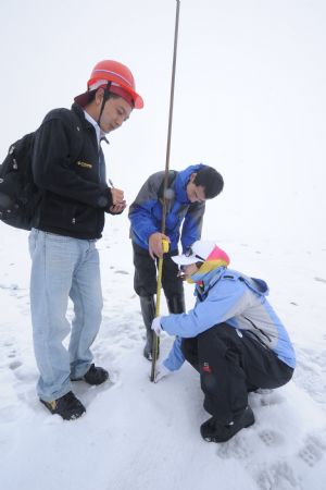 The staff of Chinese Academy of Sience observes the changes of the measuring pole in the Yulong Snow Mountain in Lijiang, southwest China's Yunnan Province.