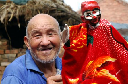 Yuan Youen, a folk artist shows a puppet of Shoulder Pole Drama, a local traveling puppet drama show in Balizhuang Village in Neihuang County, Henan Province, Aug. 23, 2009. Yuan, at his seventies, who began performing Shoulder Pole Drama when he was 25, is now the only Shoulder Pole Drama artist alive in the village. 