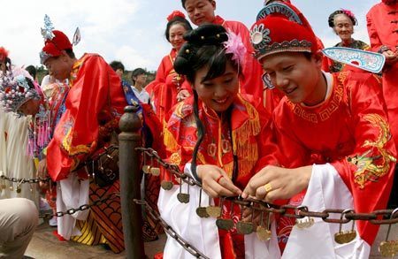 The newlyweds perform the traditional matrimonial custom of locking up the Same Heart Lock, during the 2009 large international collective weddings in traditional Chinese Custom, at the Pujiu Temple of Yongji City, north China's Shanxi Province, Aug. 26, 2009. 