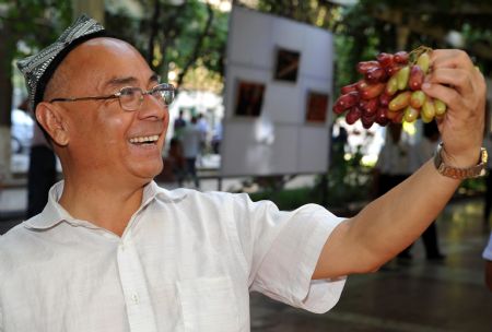 A resident checks grapes during the opening ceremony of the 18th Grape Festival of Turpan on China's Silk Road, in Turpan, northwest China's Xinjiang Uygur Autonomous Region, Aug. 26, 2009.[Zhao Ge/Xinhua]