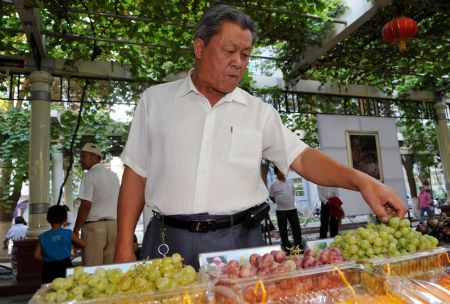 A resident tastes grapes during the opening ceremony of the 18th Grape Festival of Turpan on China's Silk Road, in Turpan, northwest China's Xinjiang Uygur Autonomous Region, Aug. 26, 2009.[Zhao Ge/Xinhua]