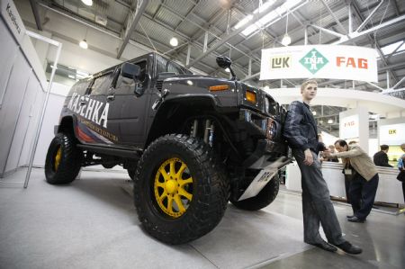A visitor has photos taken with a re-modelled Hummer SUV during the 5th Russia International Auto Show in Moscow, Russia, Aug. 26, 2009.[Lu Jinbo/Xinhua]