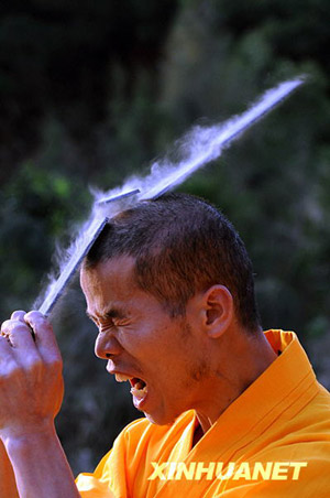 Shi Ligang, an instructor of Kungfu monks from Shaolin Temple in Quangzhou City, performs Kungfu Iron Head skill on April 9, 2009. [Jiang Kehong/Xinhua]