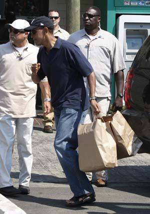 U.S. President Barack Obama carries two bags containing takeout food that he bought from Nancy's restaurant in Oak Bluffs, Martha's Vineyard, August 26, 2009. 