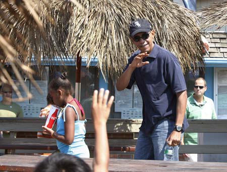 U.S. President Barack Obama waves to fellow diners as he and his daughter Sasha leave Nancy's restaurant in Oak Bluffs, Martha's Vineyard, August 26, 2009. 