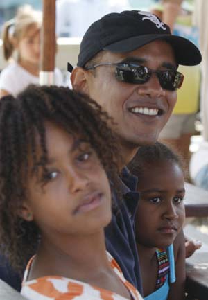 U.S. President Barack Obama sits with his daughters Malia (L) and Sasha as they wait to collect an order of takeout food at Nancy's Restaurant in Oak Bluffs, Martha's Vineyard, August 26, 2009.