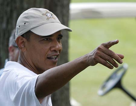 U.S. President Barack Obama points to golfers and staff in the clubhouse following a round of golf at the Mink Meadows Golf Club on Martha's Vineyard, August 25, 2009.