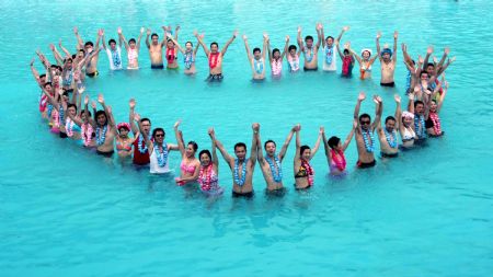The newly-wedded couples pose for photos during a group wedding ceremony held in the swimming pool at Happy Valley, a famous theme park in Shenzhen, south China's Guangdong Province, August 26, 2009. Thirty newly-wedded couples took part in the group wedding ceremony held in the swimming pool here on Wednesday. (Xinhua/Feng Ming)