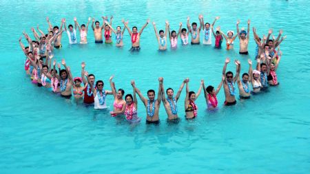 The newly-wedded couples pose for photos during a group wedding ceremony held in the swimming pool at Happy Valley, a famous theme park in Shenzhen, south China's Guangdong Province, August 26, 2009. Thirty newly-wedded couples took part in the group wedding ceremony held in the swimming pool here on Wednesday. [Feng Ming/Xinhua]