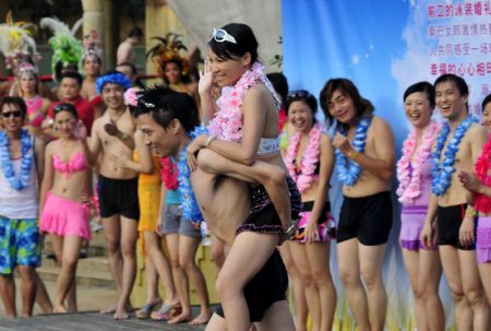 A newly-wedded couple is seen during a group wedding ceremony held in the swimming pool at Happy Valley, a famous theme park in Shenzhen, south China's Guangdong Province, August 26, 2009. Thirty newly-wedded couples took part in the group wedding ceremony held in the swimming pool here on Wednesday. [Yuan Shuiling/Xinhua]