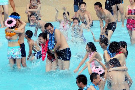 The newly-wedded couples frolic in the water during a group wedding ceremony held in the swimming pool at Happy Valley, a famous theme park in Shenzhen, south China's Guangdong Province, August 26, 2009. Thirty newly-wedded couples took part in the group wedding ceremony held in the swimming pool here on Wednesday. [Feng Ming/Xinhua] 