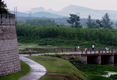 Locals take morning exercise at the east gate of Shouxian County, a famous historic and cultural site in east China's Anhui Province, on Aug. 18, 2009.