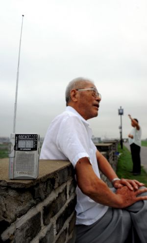 A senior man listens to the radio on the remedied ancient city-wall in Shouxian County, a famous historic and cultural site in east China's Anhui Province, Aug. 18, 2009.[Xinhua/Tao Ming]