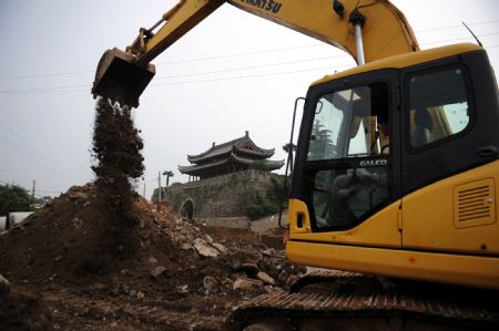A bulldozer works on a construction site between the east gate and south gate of the ancient city-wall in Shouxian County, a famous historic and cultural site in east China's Anhui Province, on Aug. 17, 2009.(Xinhua/Tao Ming) 