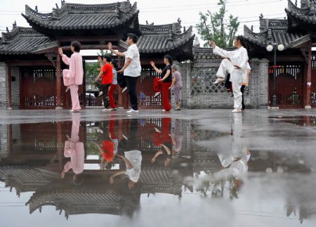 Locals do taijiquan, a kind of traditional Chinese shadow boxing, in front of Confucian temple in Shouxian County, a famous historic and cultural site in east China's Anhui Province, on Aug. 18, 2009.(Xinhua/Tao Ming)