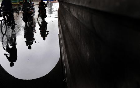 Shadows of locals are reflected in water at the south gate of the remedied ancient city-wall in Shouxian County, a famous historic and cultural site in east China's Anhui Province, on Aug. 18, 2009.(Xinhua/Tao Ming)