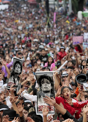 Michael Jackson fans hold up his poster as they dance to 'Thriller' in celebration of the late singer's 51st birthday in Mexico City August 29, 2009. Over 12,000 fans danced to Michael Jackson's 'Thriller' at the event, breaking a Guinness world record.