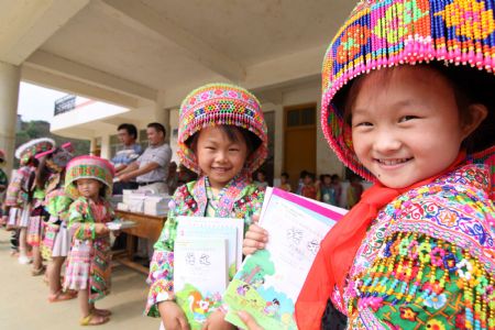 Girl student Wang Qiao (1st R) of a Hope School receives free school books in Longlin county, southwest China's Guangxi Zhuang Autonomous Region, August 31, 2009.(Xinhua/Lin Bin)