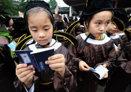 New pupils receive the book, The Analects of Confucius, during a ceremony in a Confucius temple in Nanjing,east China's Jiangsu province, August 31, 2009.(Xinhua/Reuters Photo) 