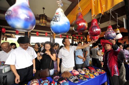 Tourists choose works of handicraft at a special local products fair during the Nv'erhui Festival in Enshi autonomous prefecture of the Tujia and Miao ethnic groups in central China's Hubei Province, Aug. 31, 2009.(Xinhua/Hao Tongqian)