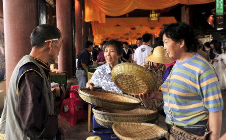 Tourists choose works of handicraft at a special local products fair during the Nv'erhui Festival in Enshi autonomous prefecture of the Tujia and Miao ethnic groups in central China's Hubei Province, Aug. 31, 2009.(Xinhua/Hao Tongqian) 