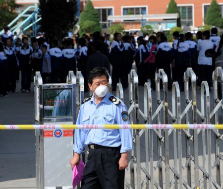 A health official guards at the entrance of a middle school in Lanzhou, capital of northwest China's Gansu Province, Aug. 31, 2009. A/H1N1 flu cases broked out in the middle school there since Aug. 28, and the confirmed infected patients grew to 26 till 3 pm Aug. 30. (Xinhua/Han Chuanhao)