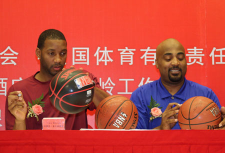 NBA player Tracy McGrady (L) of Houston Rockets signs on a basketball which is going to be auctioned during an opening ceremony and a press conference of Warming China Charity Tour sponsored by the China Red Cross Foundation in Beijing, capital of China, Aug. 31, 2009. (Xinhua/Wang Yongji)