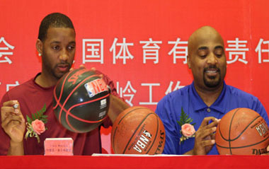 NBA player Tracy McGrady (L) of Houston Rockets signs on a basketball which is going to be auctioned during an opening ceremony and a press conference of Warming China Charity Tour sponsored by the China Red Cross Foundation in Beijing, capital of China, Aug. 31, 2009.