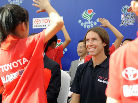 NBA player Steve Nash(R) is saluted by students in a primary school for rural migrant workers' children during the NBA Cares Program in Changchun, capital of northeast China's Jilin Province, Aug. 31, 2009. (Xinhua/Wang Haofei) 