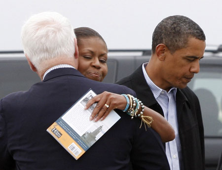 U.S. first lady Michelle Obama (C) hugs U.S. Congressman Bill Delahunt alongside President Barack Obama as they step aboard Air Force One at the Cape Cod Coast Guard Air Station, en route to Washington following their vacation on Martha's Vineyard, August 30, 2009. 