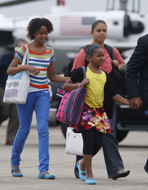 U.S. President Barack Obama's daughters Sasha (R) and Malia prepare to board Air Force One at the Cape Cod Coast Guard Air Station, en route to Washington following their family vacation on Martha's Vineyard, August 30, 2009. Behind is White House staffer Kristen Jarvis. 