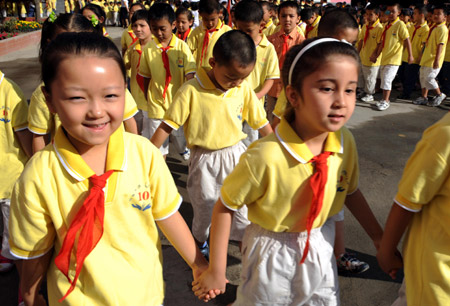 Students from Urumqi No. 10 Primary School walk to classrooms on the first day of the new semester in Urumqi, capital of northwest China's Xinjiang Uygur Autonomous Region, Sep. 1, 2009. (Xinhua/Wang Fei)