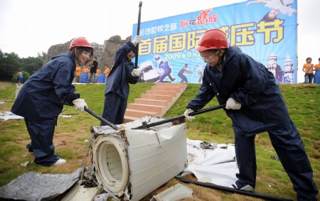 Tourists try to smash a scrapped washing machine during a pressure releasing activity held in a park in Changsha, capital of central China's Hunan Province, Sept. 1, 2009. (Xinhua/Li Ga)
