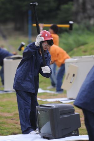 A tourist tries to smash a scrapped television set during a pressure releasing activity held in a park in Changsha, capital of central China's Hunan Province, Sep. 1, 2009. (Xinhua