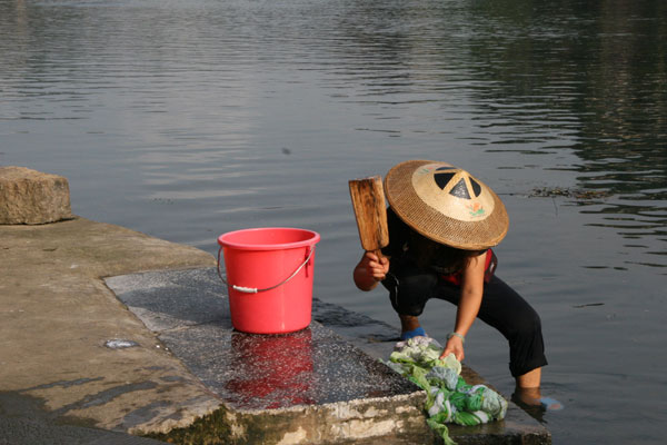 A local woman washes clothes in Tuojiang river. [Photo:CRIENGLISH.com/Duan Xuelian] 