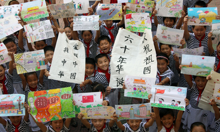 Pupils hold high their respective works of talent finished during the summer vacation for a collective presentation, as they enthusiastically present their versatile talents and skills in hand-making, painting, calligraphy, etc, which they learned and improved as a result of less home works and more social practices during the summer holidays, in the very first day of the new semester, at the Junshan Road Elementary School, in Zaozhuang, east China's Shandong Province, Sept. 1, 2009. (Xinhua/Sun Zhongzhe) 