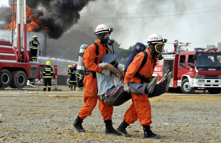 Two fire fighters carry an "injured" person in their rescue effort, during the 2009 Tianfu-Nanchong Counterterror Emergency-Disposal Joint Manoeuvre, which involves over 1,300 personnel from Fire Control, Public Security, Armed Police, Transports and Communications and other 20 departments to engage in drillings of explosive-removal, fire extinguishment, mass evacuation, etc, in a bid to boost inter-cities cooperative capacities to guard against and deter terror attacks and accidents, in Nanchong, southwest China