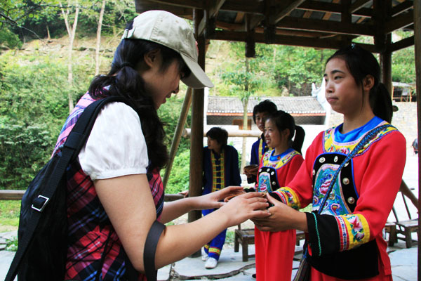 Girls dressed in Miao costumes offer us homemade rice wine to welcome us. [Photo:CRIENGLISH.com/Duan Xuelian] 