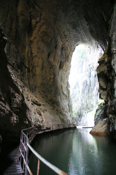 The stone cave is dark and damp, with a narrow wooden passage. [Photo:CRIENGLISH.com/Duan Xuelian]