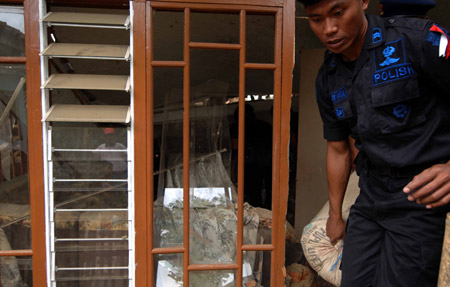 A policeman helps quake victims to transfer food from the destroyed houses in Tasik Malaya of West Java, Indonesia, Sept. 3, 2009. (Xinhua/Yue Yuewei)