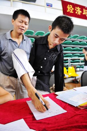 Young man without arms Yang Bin fills registration forms with his foot on the first day of the new term at Three Gorges University in Yichang, central China's Hubei province, Sept. 6, 2009. [Huang Xiang/Xinhua]