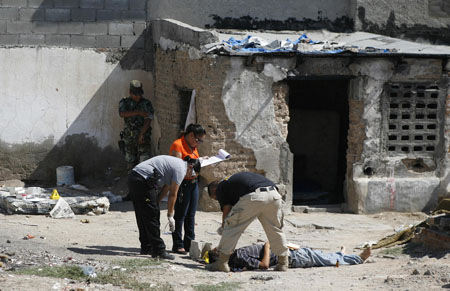 Forensic workers inspect the body of a man gunned down at a deserted house in an impoverished neighbourhood of the border city of Ciudad Juarez, September 6, 2009. The man was killed by a shot to the head, according to local media.[Xinhua/Reuters]