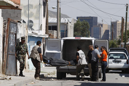 Forensic workers remove the body of a man gunned down at a deserted house in an impoverished neighbourhood of the border city of Ciudad Juarez, September 6, 2009.[Xinhua/Reuters]