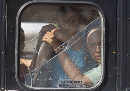 A woman and her daughter look at a crime scene where hitmen killed two men in the border city of Ciudad Juarez, September 6, 2009. Four men were travelling in a truck loaded with roosters when they were attacked on Sunday afternoon in a drive-by shooting, according to local media.[Xinhua/Reuters]