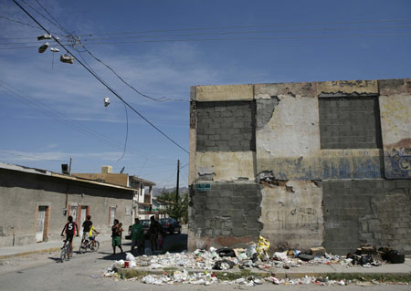 Residents walk on a street in an impoverished neighbourhood of the border city of Ciudad Juarez, September 6, 2009.[Xinhua/Reuters]